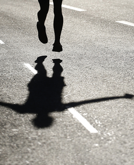 Der Schatten eines Läufers auf einer Straße