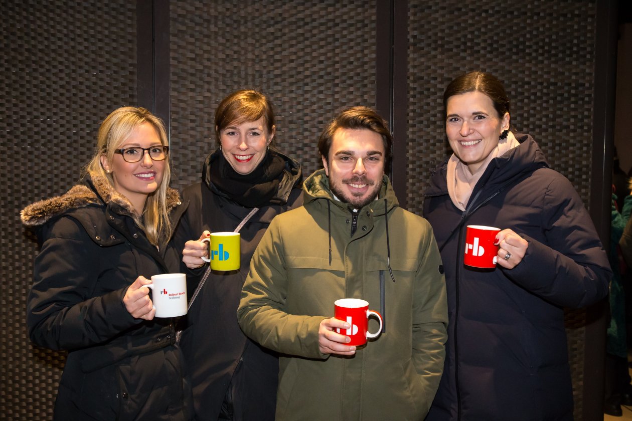 Gäste zeigen Becher der Robert Bosch Stiftung