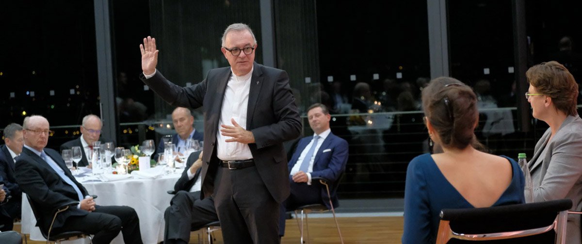 Ein Mann steht inmitten des Saales und gestikuliert