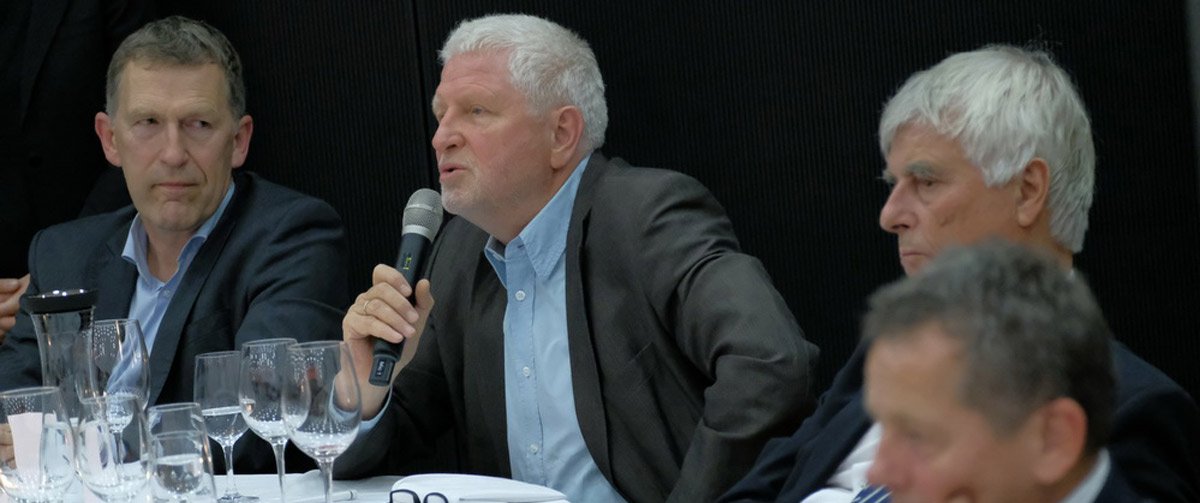 Ein Mann aus dem Publikum stellt eine Frage und sitzt zwischen anderen Männern