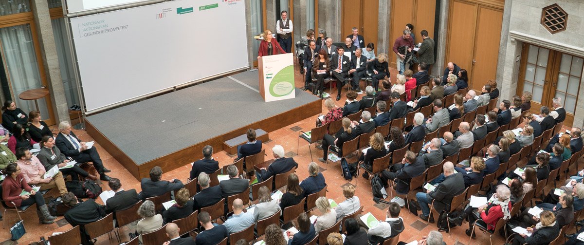 Blick von oben auf die Veranstaltung mit Bühne, Rednerpult und Publikum