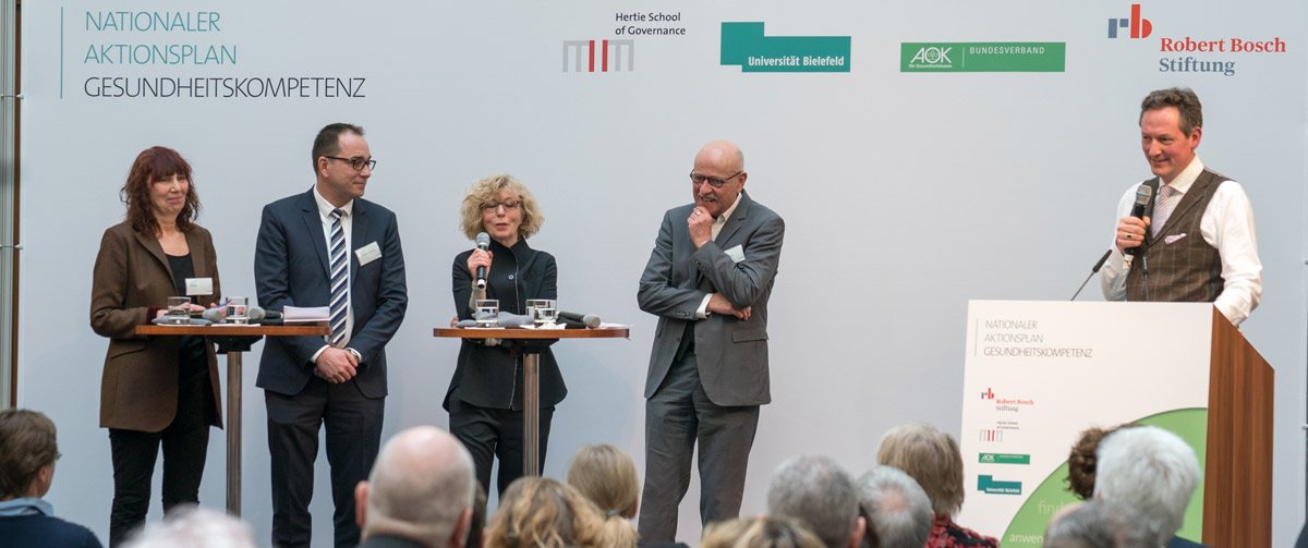 Eckart von Hirschhausen is on the lectern and next to him stand four people