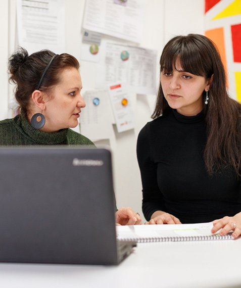 Zwei Frauen sitzen vor einem Laptop