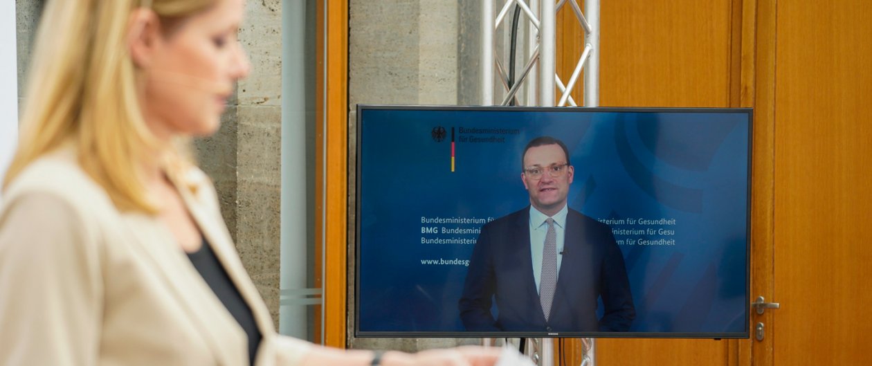 Gesundheitsminister Spahn bei Videobotschaft auf großem Bildschirm