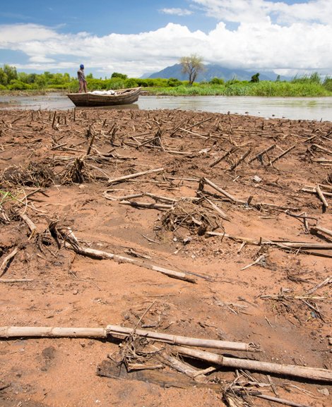 Ein vertrocknetes Feld, im Hintergrund ein Boot im Wasser