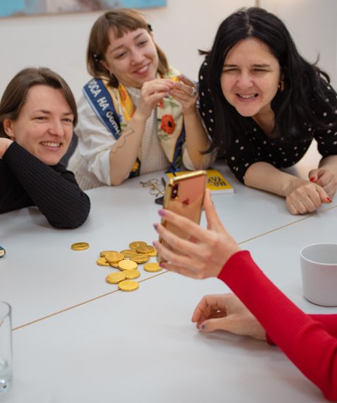 Junge Frauen lachen miteinander über ein Handybild.