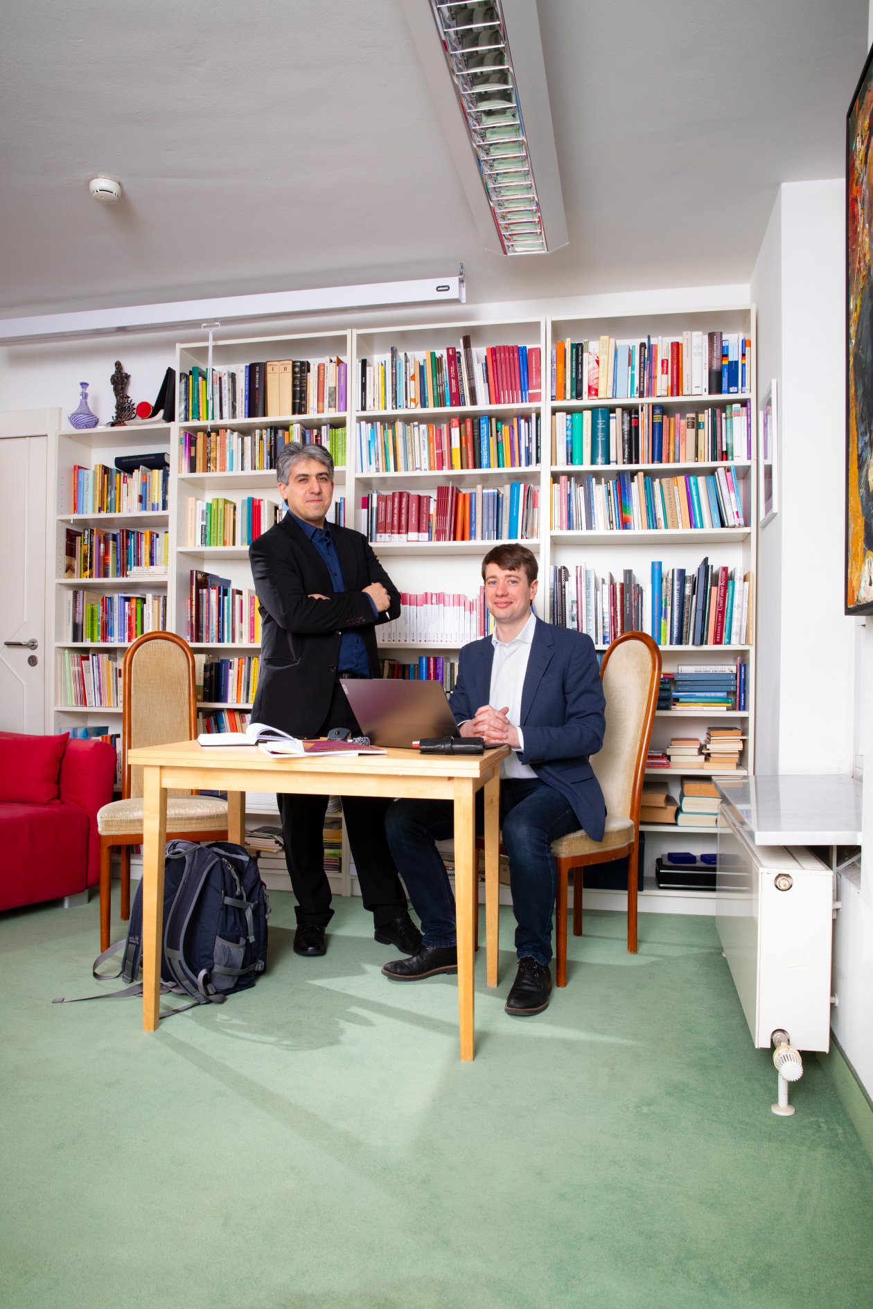 Zwei Männer an einem Tisch vor einer Bücherwand