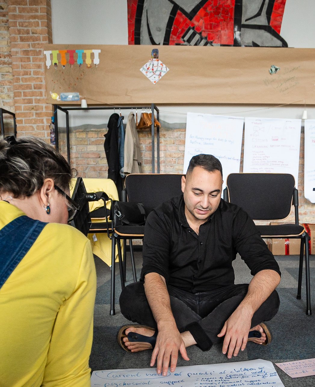 Mann sitzt auf dem Boden und beschreibt ein Plakat