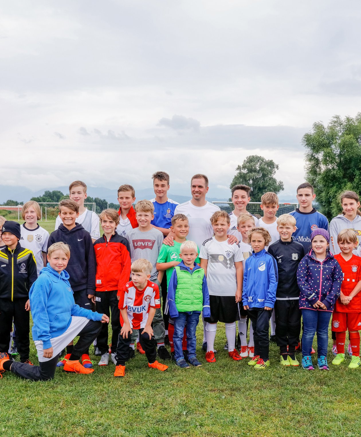 Eine Gruppe von Kindern steht auf einer Wiese. Mittendrin steht Philipp Lahm.