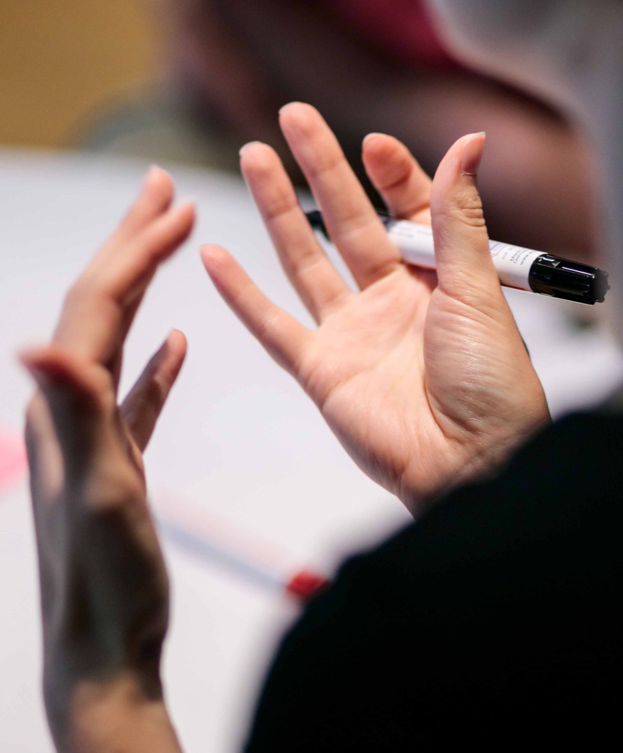 Eine Frau gestikuliert mit ihren Händen und hält einen Stift in der Hand