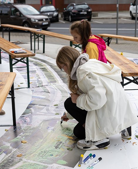 Zwei Mädchen knien über einer Skizze am Boden