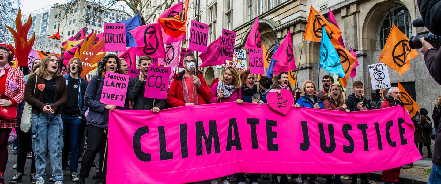 Demonstranten halten ein Banner, auf dem in Großbuchstaben Klimagerechtigkeit steht