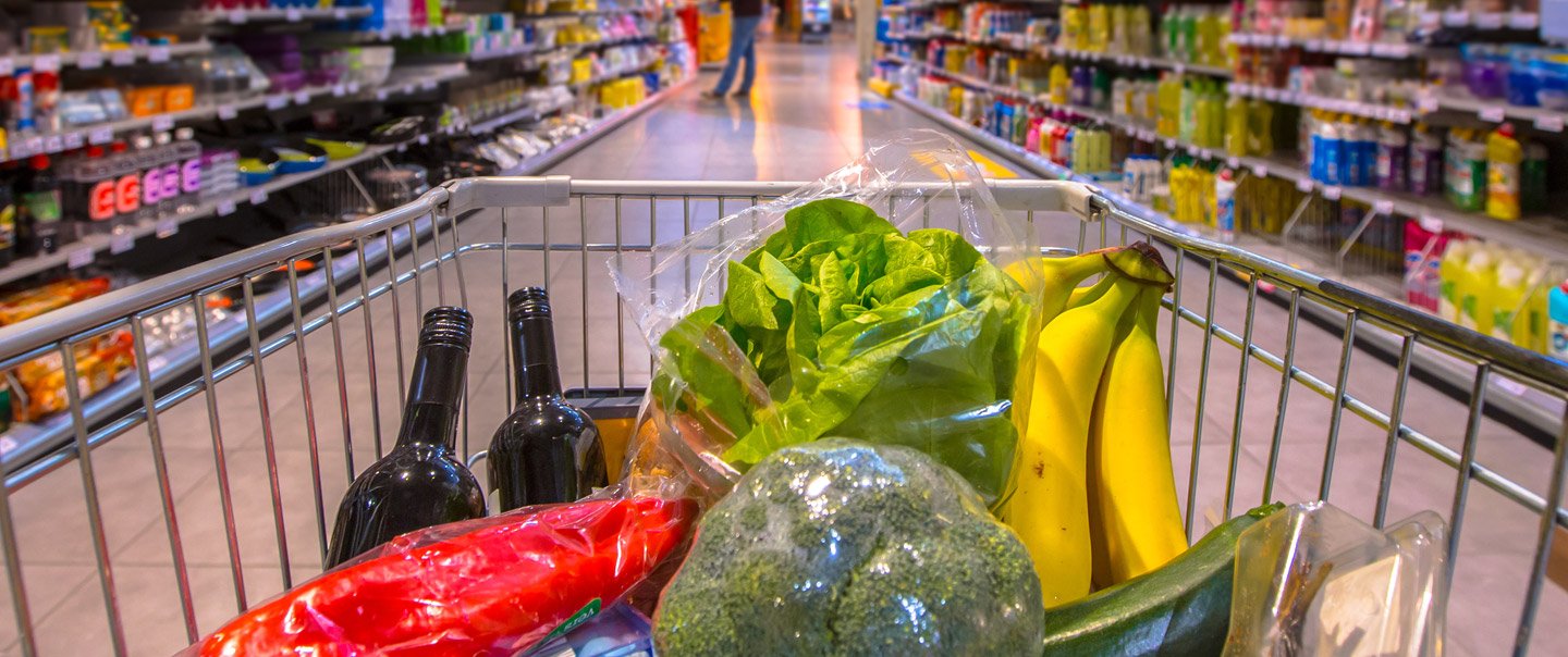 Blick in einen vollen Einkaufswagen mit verschiedenen Lebensmittel in der Mitte eines Supermarktes