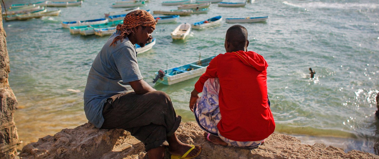African men sitting at the sea.