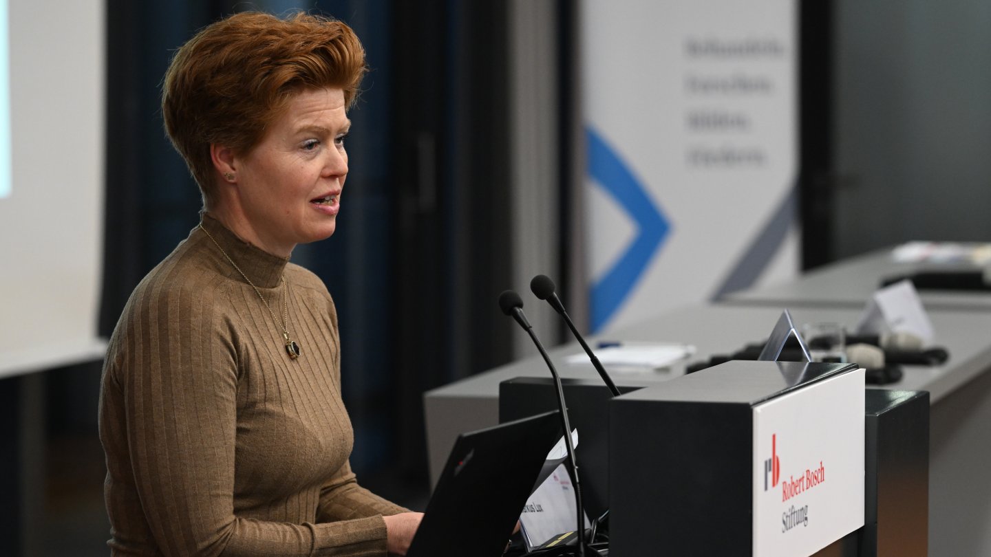 Susanne Melin stands at the lectern and speaks into the microphone