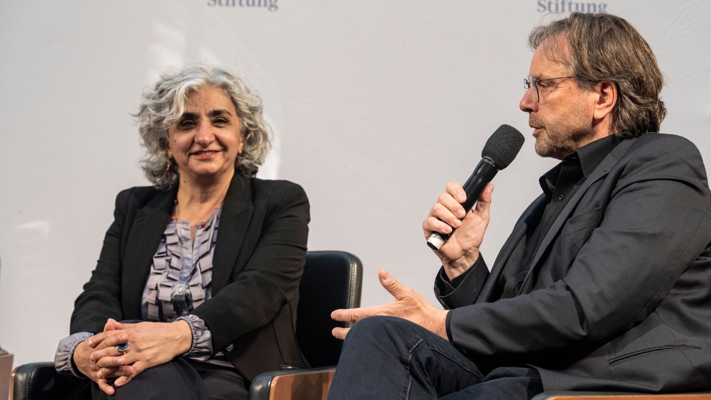 Dr. Delal Atmaca from the umbrella organization of migrant organizations and Michael Groß, President of the Federal Association of Welfare Services in Germany, sit on a podium