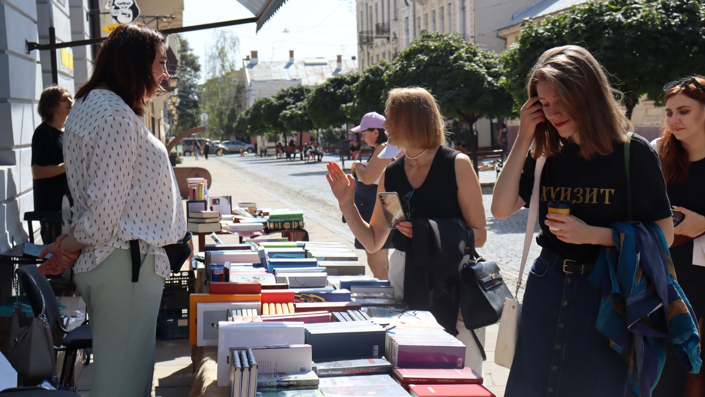 Menschen schauen sich die Auslage auf einem Büchertisch am Straßenrand an