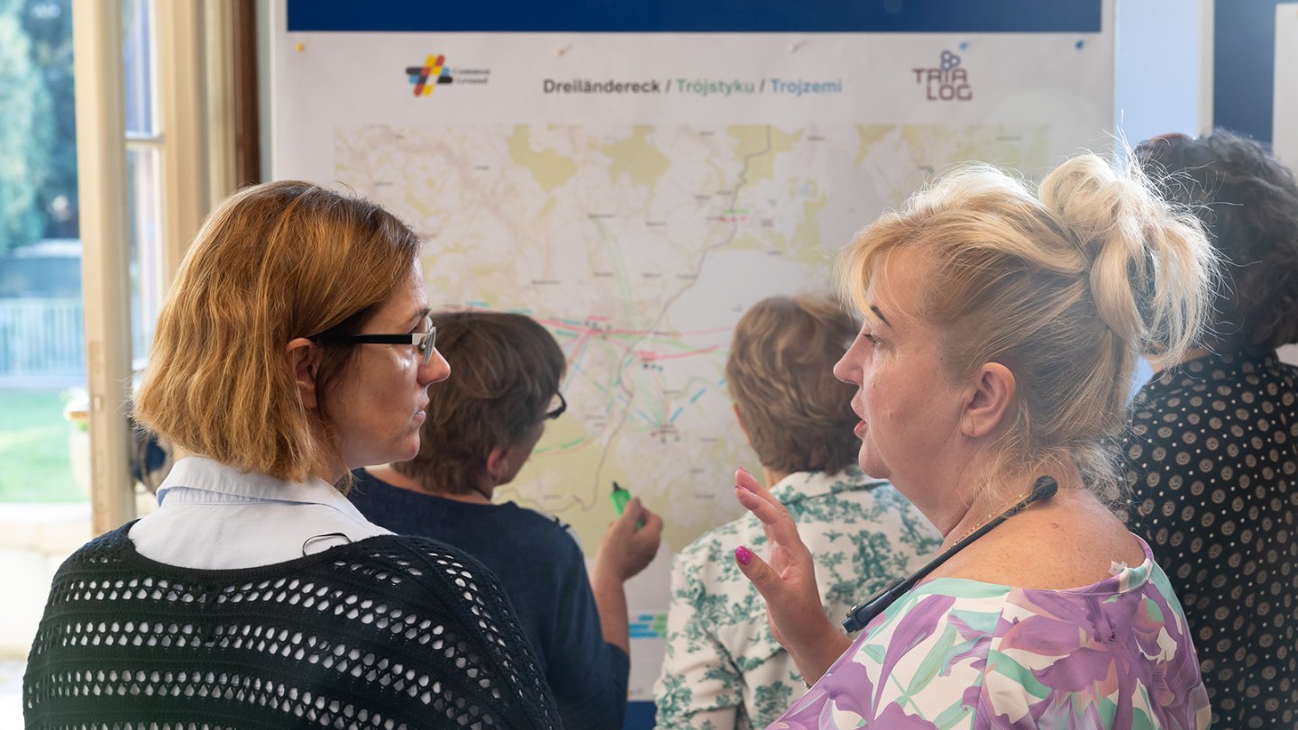 Zwei Frauen sprechen miteinander, im Hintergrund arbeiten zwei andere an einem Workshopplakat