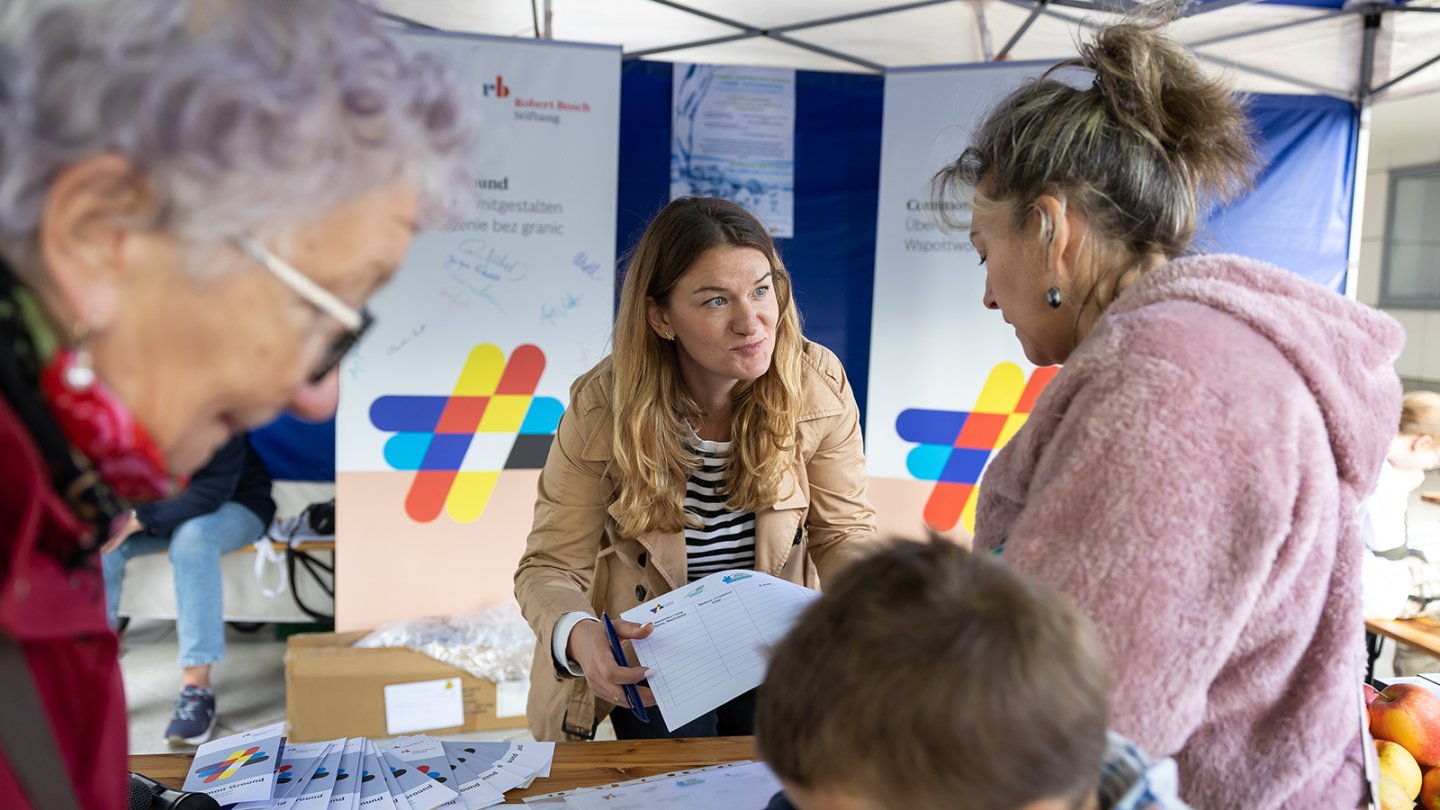 Eine Frau berät eine andere in einem Infostand.