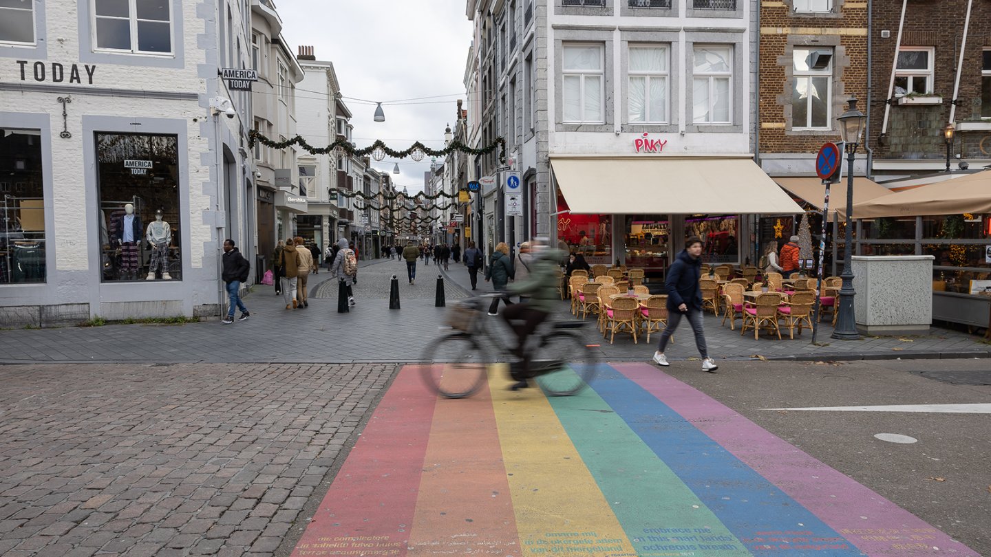 Cyclist rides over a rainbow-colored street marking.