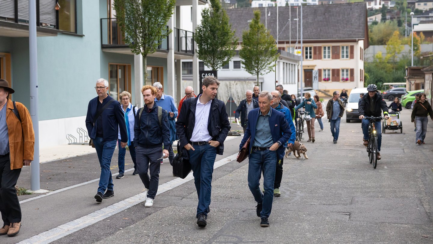 Men strolling down a street, engaged in conversation.