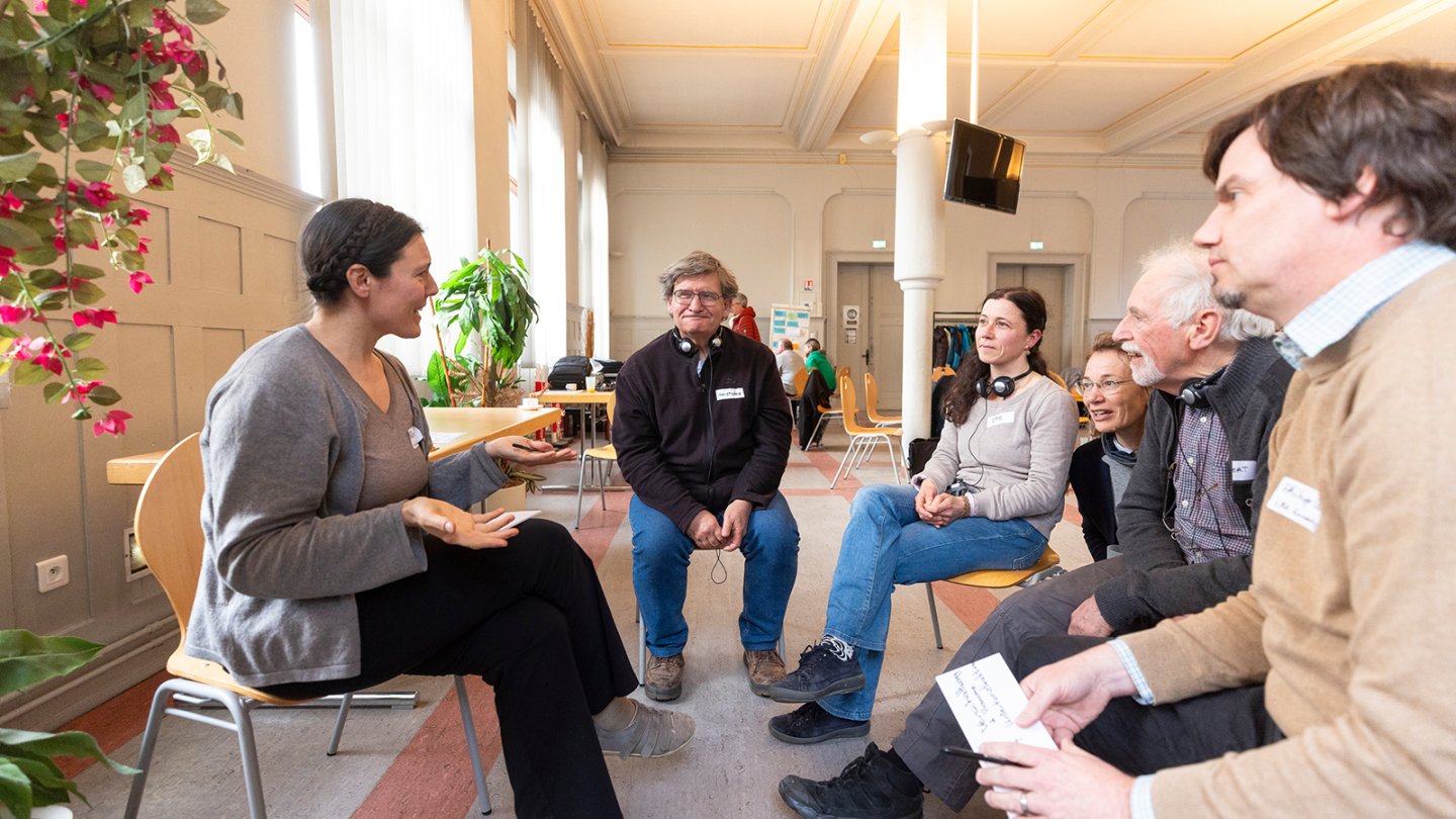In a circle of chairs, a woman shares her insights with the group.