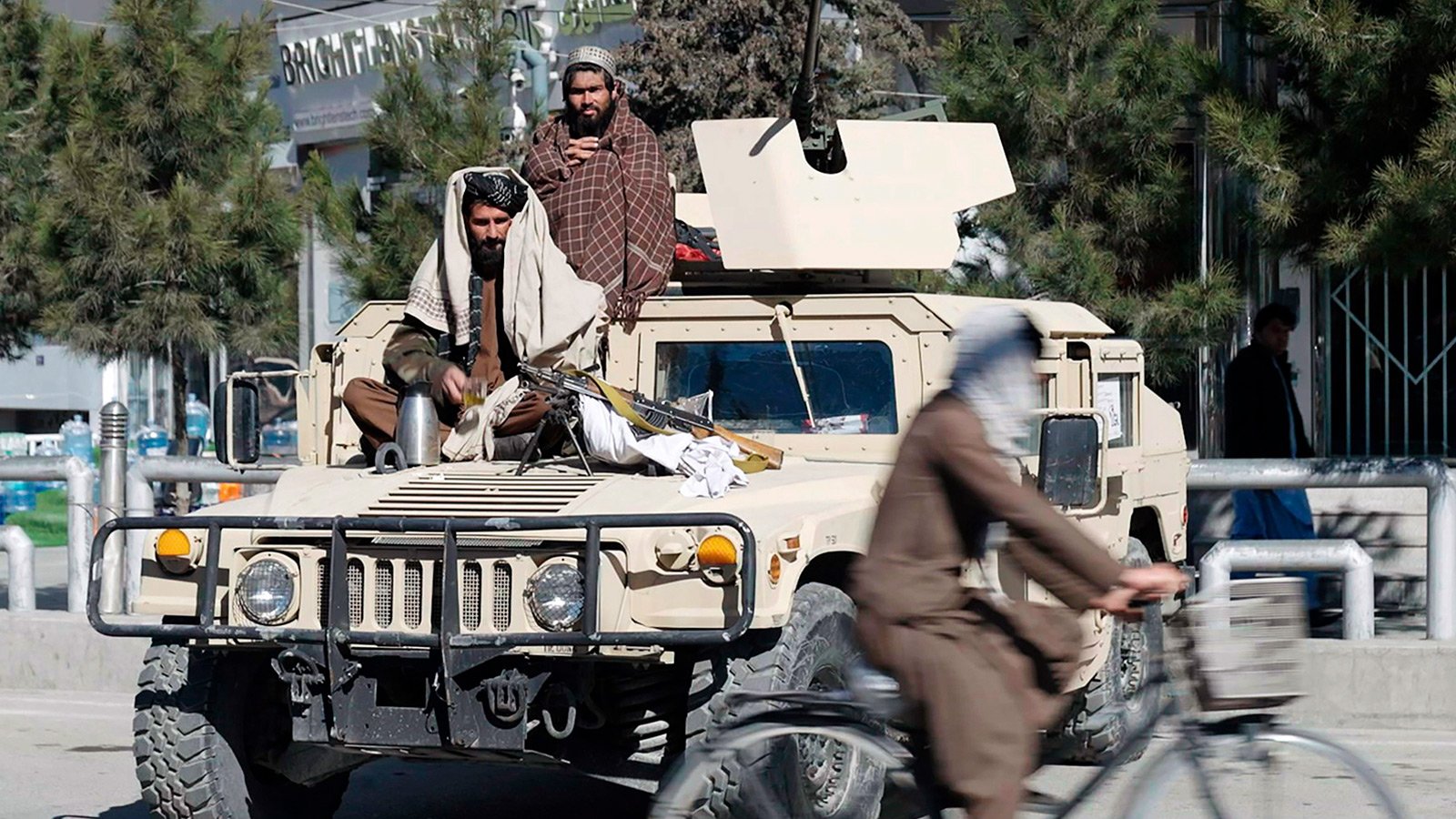 Bewaffnete Taliban sitzen auf einem Militärfahrzeug in der Stadt