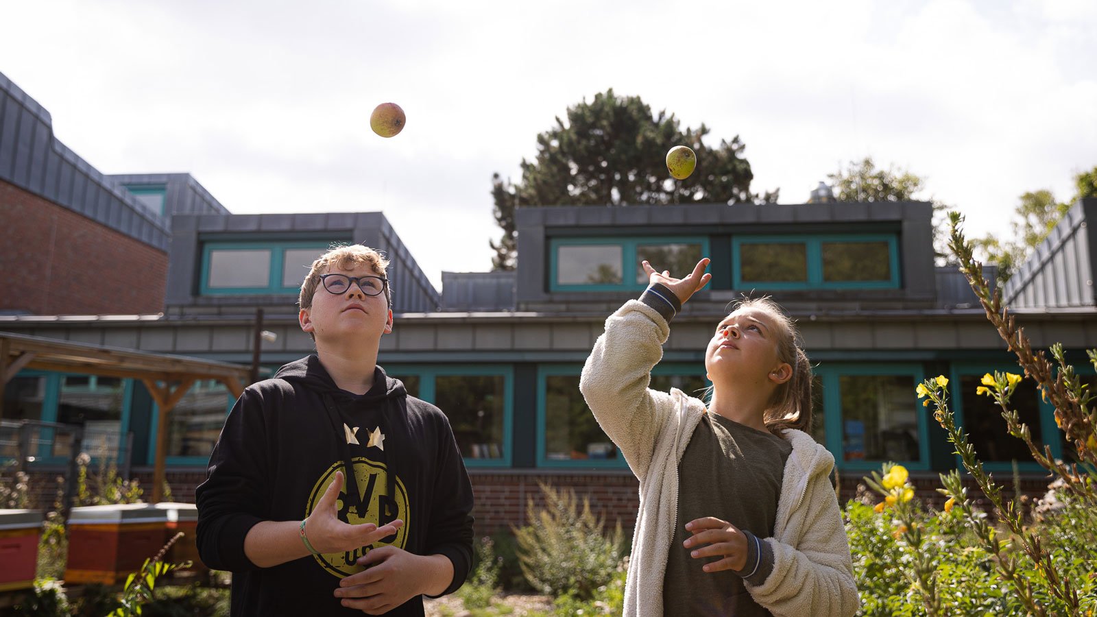 Two children throw their balls in the air