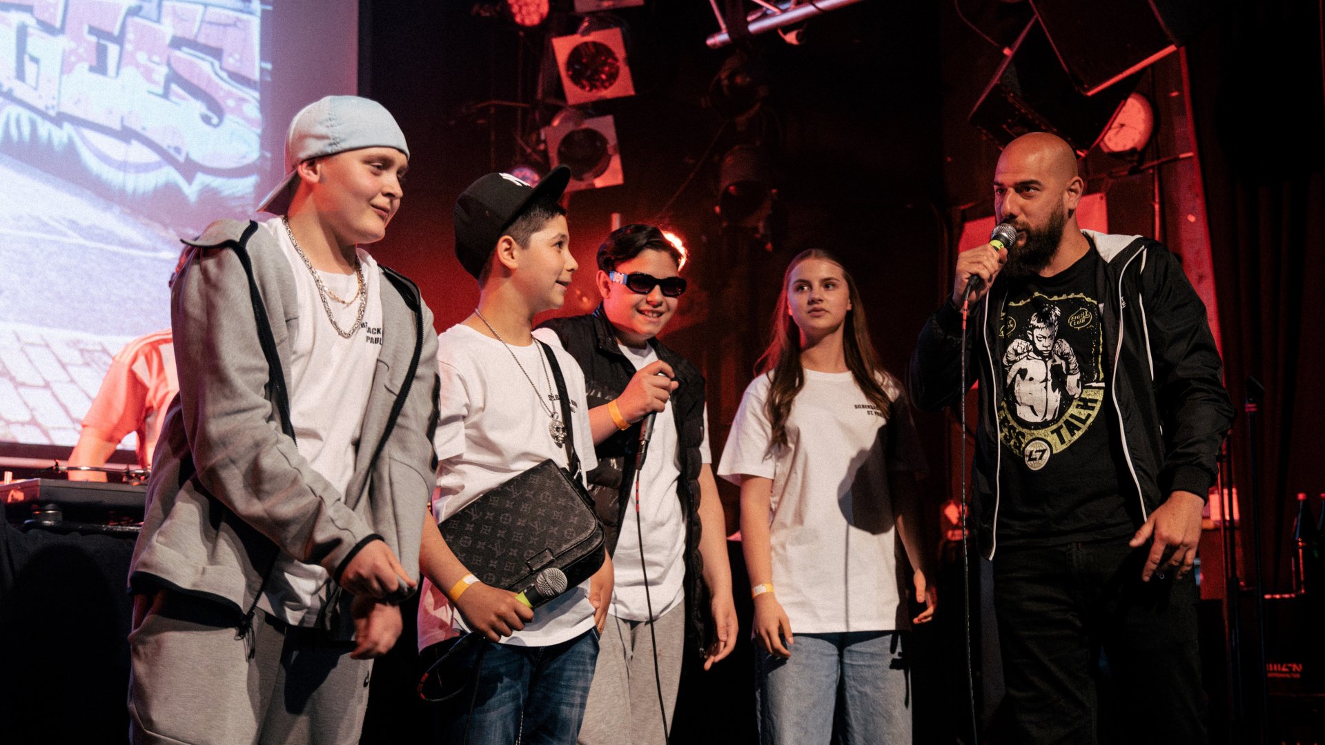 Children and an adult stand on a stage with microphones