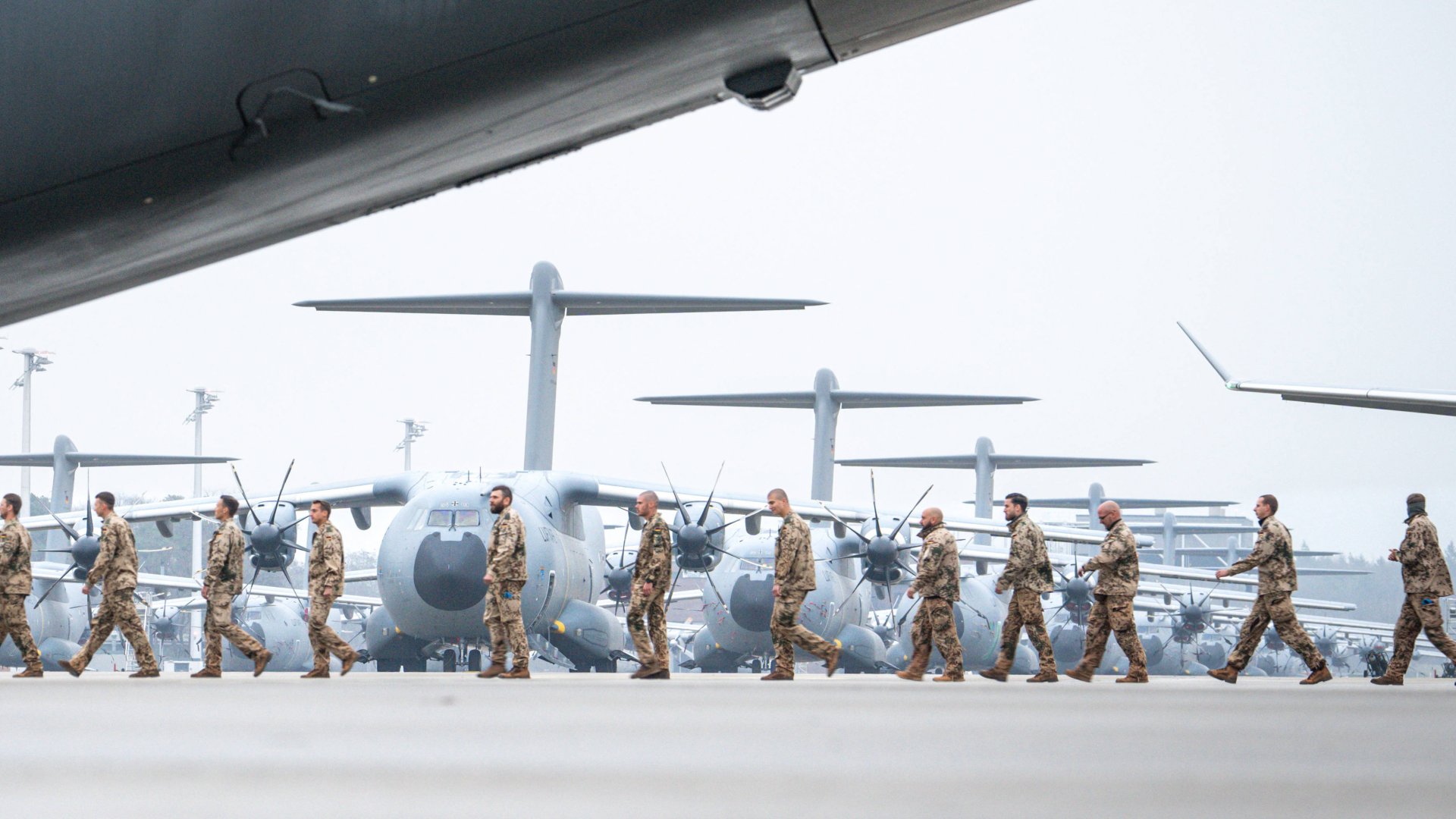 Soldiers walking across an airfield to an aircraft