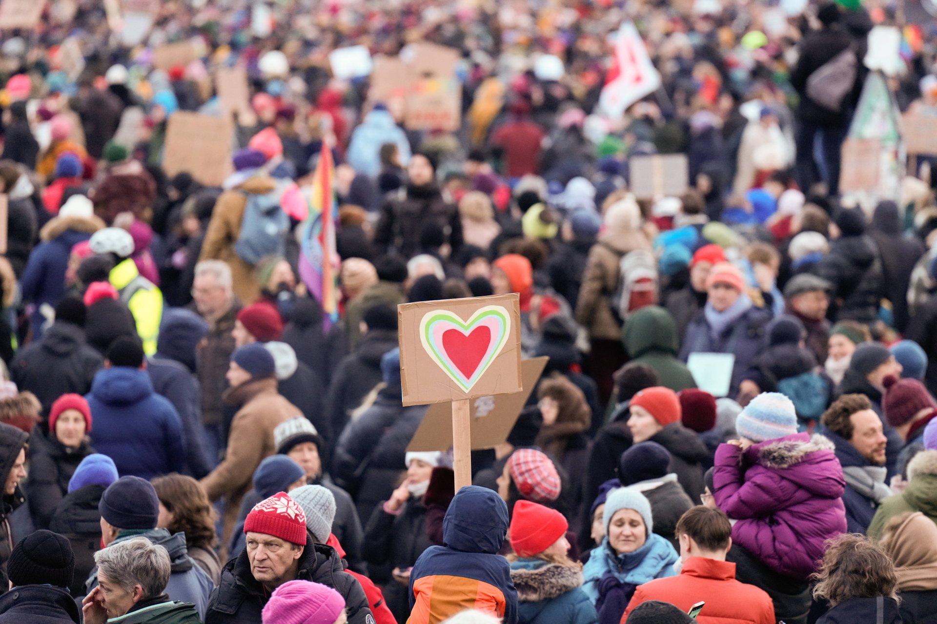 People at a demonstration, a child holds a cardboard sign with hearts on it