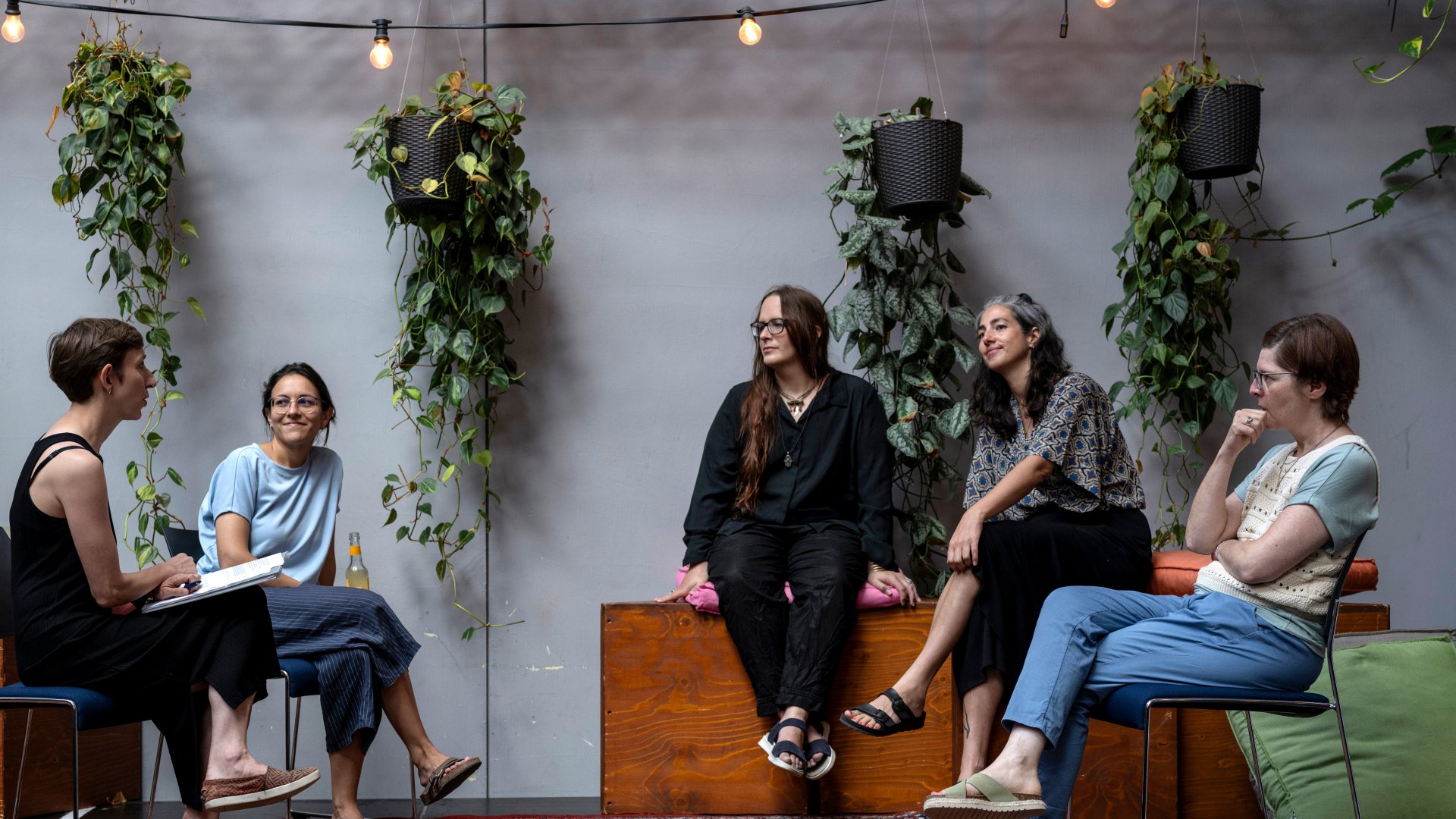 Four women sit in a semicircle and discuss