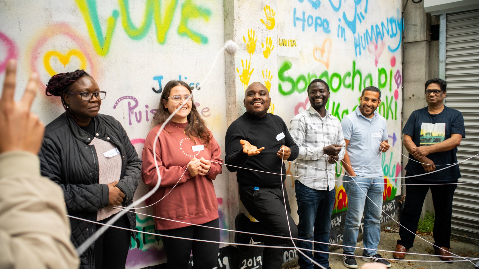 Menschen stehen im Halbkreis und werfen sich ein Wollknäuel zu