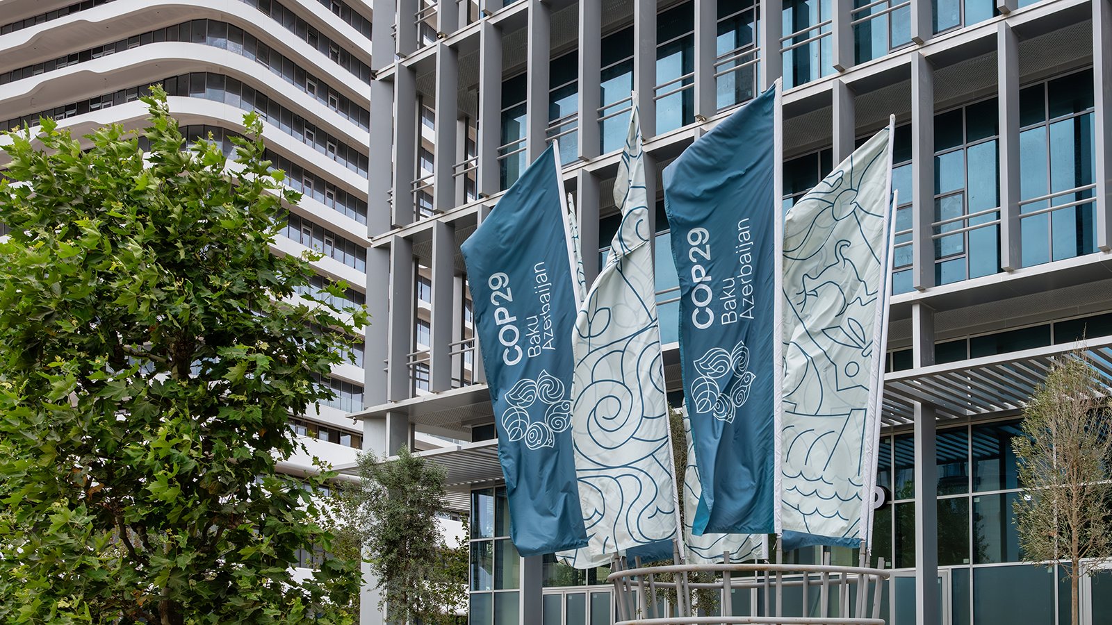 Flags of the COP29 in front of tower blocks.