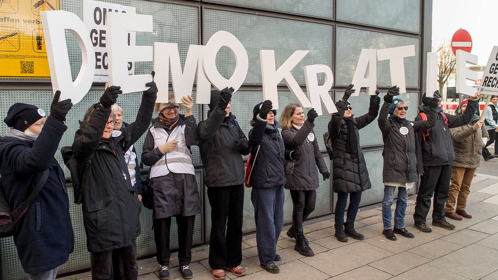 Omas gegen Rechts halten Buchstaben hoch, die das Wort Demokratie bilden