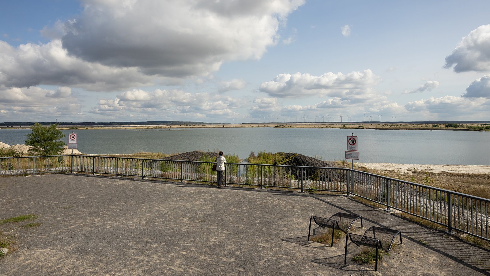 Eine Frau steht allein auf einer Uferpromenade.
