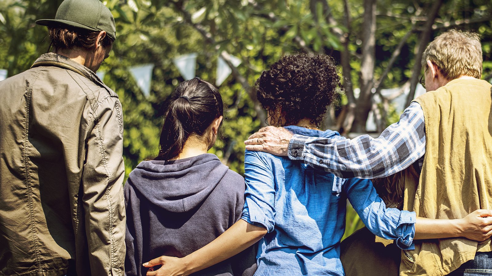 Rear view of four people with their arms around each other's shoulders