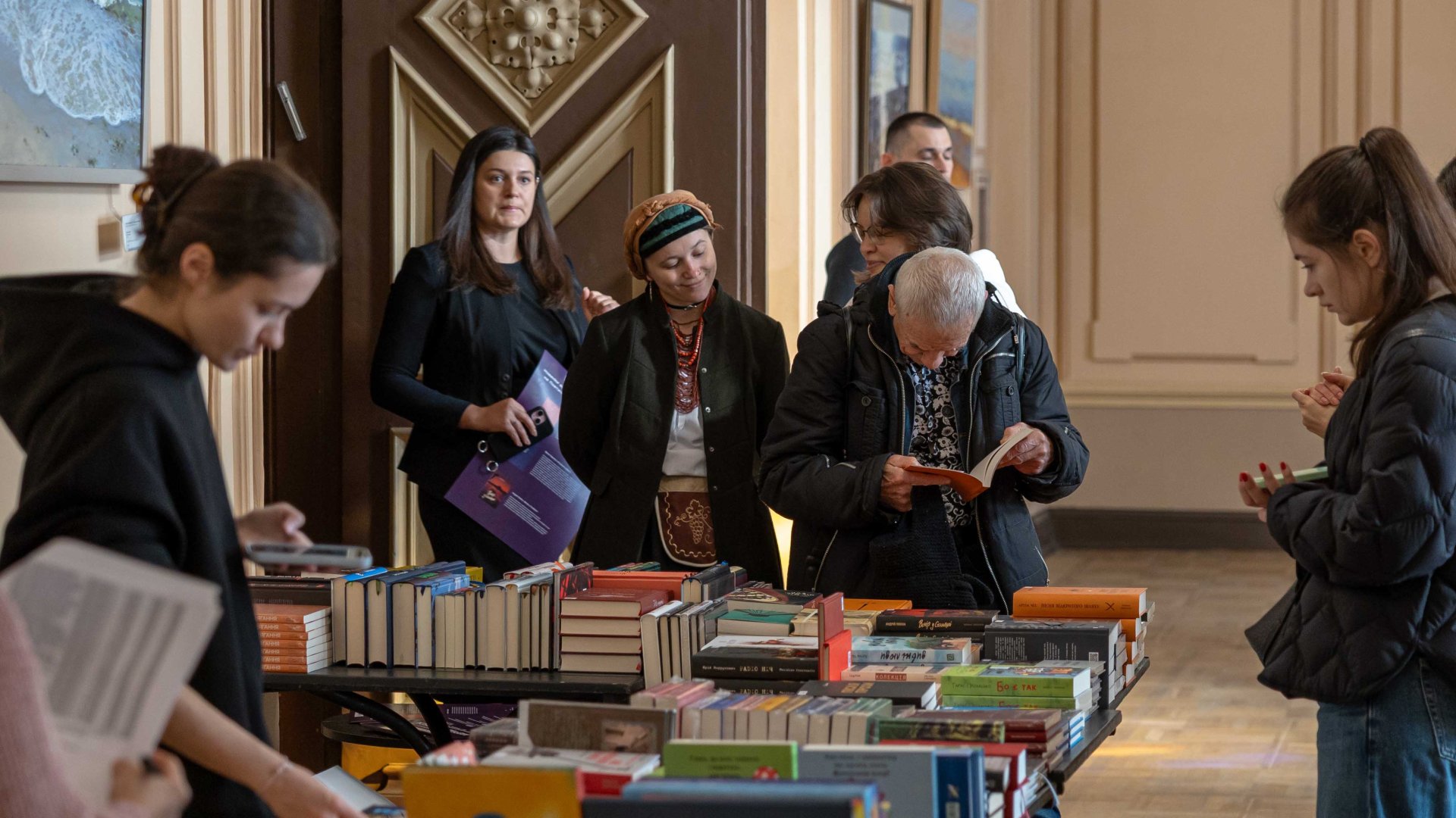 Menschen stehen an einem Büchertisch beim Literaturfestival Meridian in Odesa und lesen