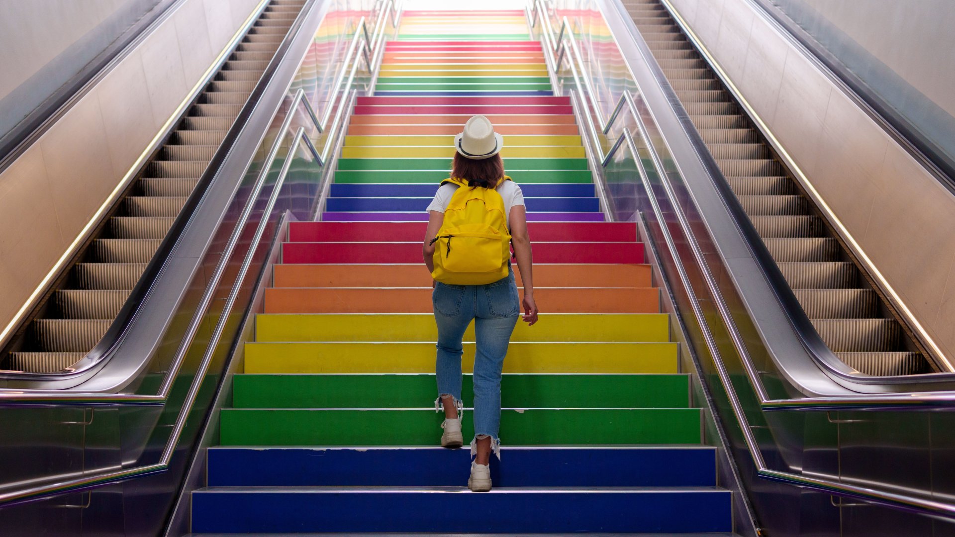 Mensch geht eine Treppe mit bunten Stufen hoch