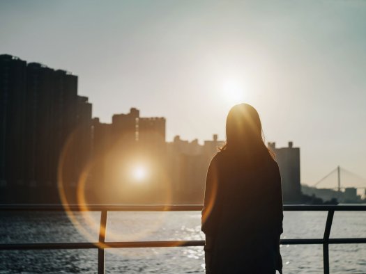 Eine Frau auf einer Brücke im Gegenlicht.