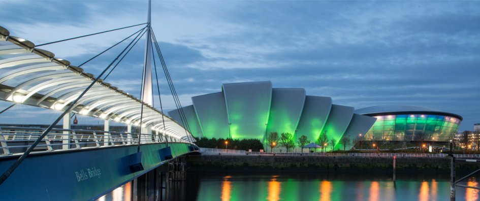 Next to a bridge stands the green-lit building where the COP26 is taking place