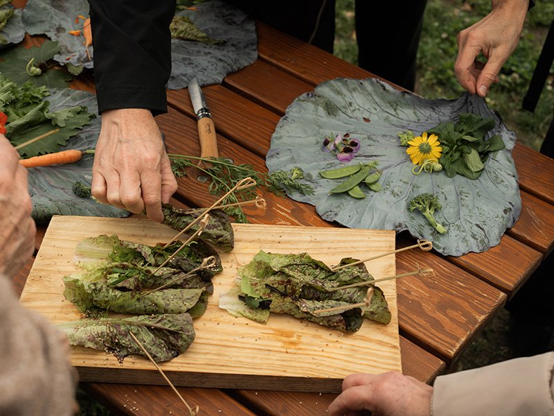 Hände richten Salat und essbare Blüten an
