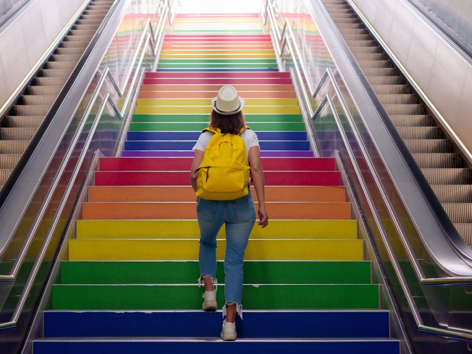 Mensch geht Treppe mit bunt gefärbten Stufen hoch