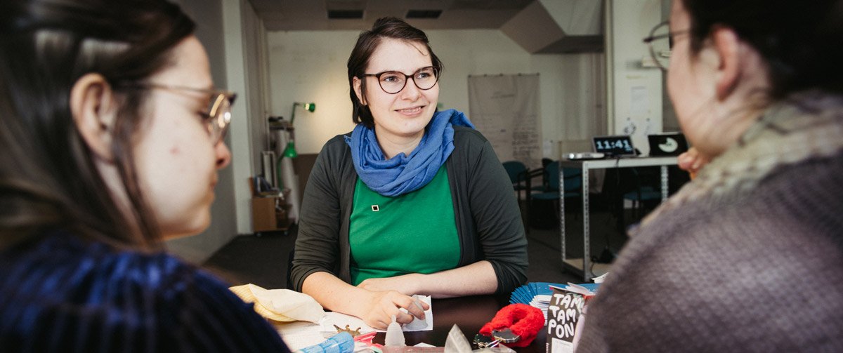 Expertin und Studentinnen diskutieren am Tisch